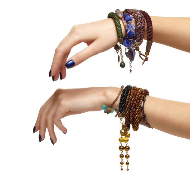 Female hands with handmaid bijouterie bracelets isolated on white background. Nails with blue manicure and wrists are with bijouterie bracelets.