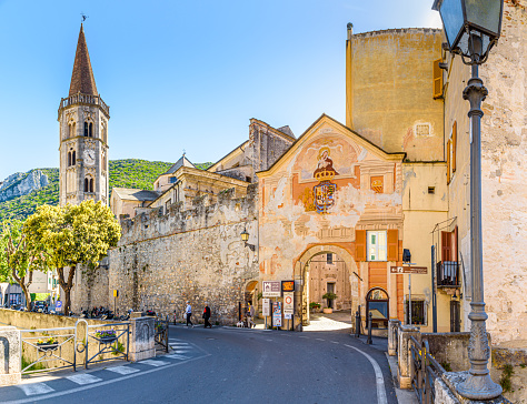 Finalborgo, Finale Ligure, Italy. May 5, 2021. View of the external facade of Porta Reale and of the ancient walls with the bell tower of the Church of San Biagio on the left.