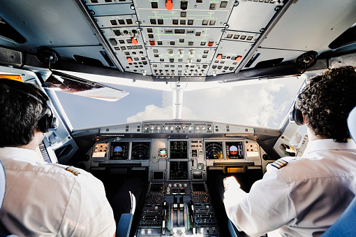 Portrait of a male flight instructor sitting in cockpit looking behind at the camera. Male pilot in uniform in flight simulator.