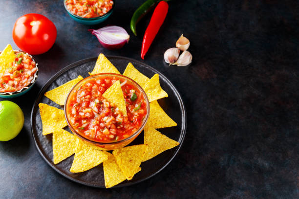 istock Salsa sauce and nacho chips on a dark background. Mexican salsa sauce and ingredients. Mexican food. Copy space. Top view 1370101204
