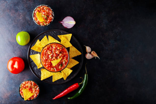 istock Salsa sauce and nacho chips on a dark background. Mexican salsa sauce and ingredients. Mexican food. Copy space. Top view 1370101215