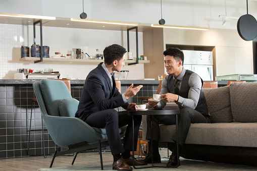 Two Chinese businessmen talking and drinking coffee in a coffee shop