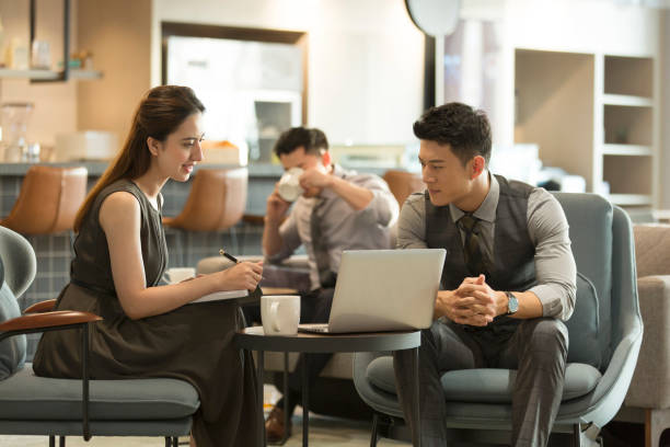 istock Young business people using laptop in coffee shop 1370101412