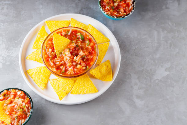istock Salsa dip and nacho chips on a white plate. Tortilla chips and salsa sauce in bowl on a gray background. Mexican cuisine. Top view. Copy space 1370102216