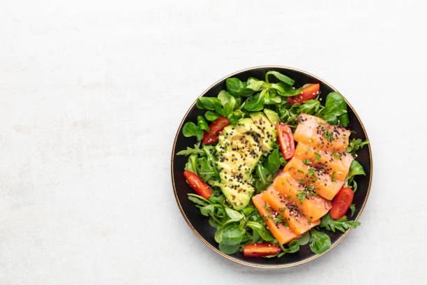 istock Salmon fish fillet with fresh salad, avocado top view. 1370102810