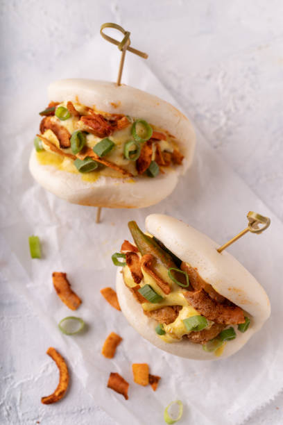 asiatische fusion veganer weißer soft bao mit okra, würzigen kokosflocken, mayo und frühlingszwiebeln - baozi stock-fotos und bilder