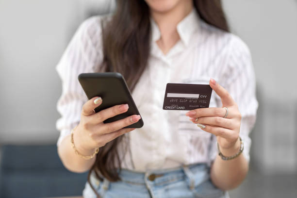 Close up. woman holding smartphone and using credit card for online shopping. stock photo