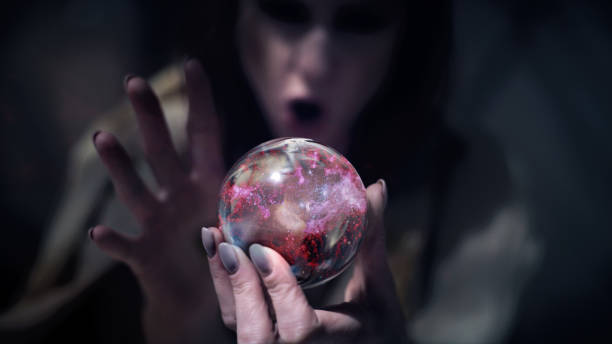 Woman fortune telling with glass sphere. Smiling and gesturing. Pink, digitally generated cosmic dust inside sphere