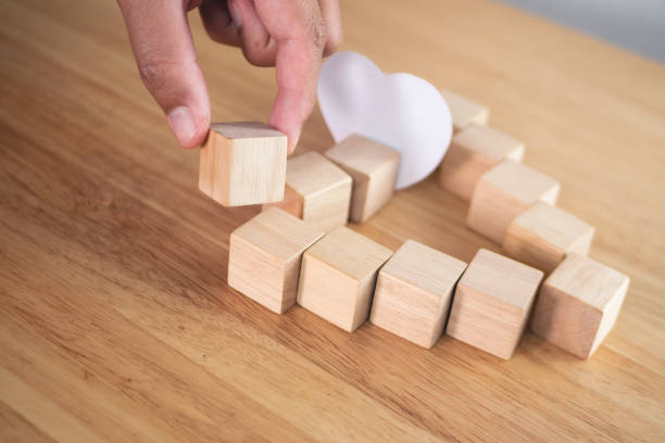 istock Love connection concept. Someone assembles wood blocks to  be heart shape. 1370108873