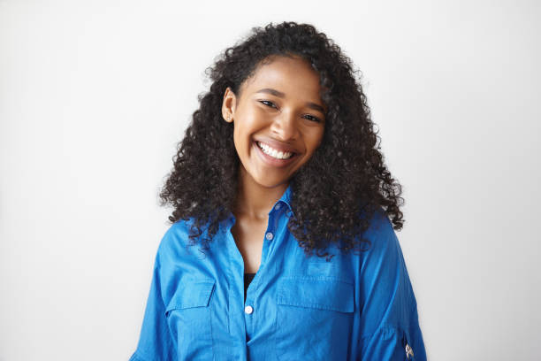 Picture of gorgeous African student girl wearing casual blue shirt rejoicing at good results on exams, smiling broadly. Beautiful young black woman looking at camera with charming cute smile Picture of gorgeous African student girl wearing casual blue shirt rejoicing at good results on exams, smiling broadly. Beautiful young black woman looking at camera with charming cute smile alternative pose photos stock pictures, royalty-free photos & images