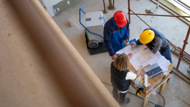 istock Women talking with two workers, reading building plans 1370116727