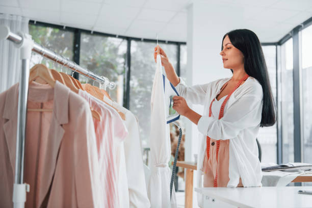 istock Irons clothes. Seamstress is in her office that is with different clothes 1370118135