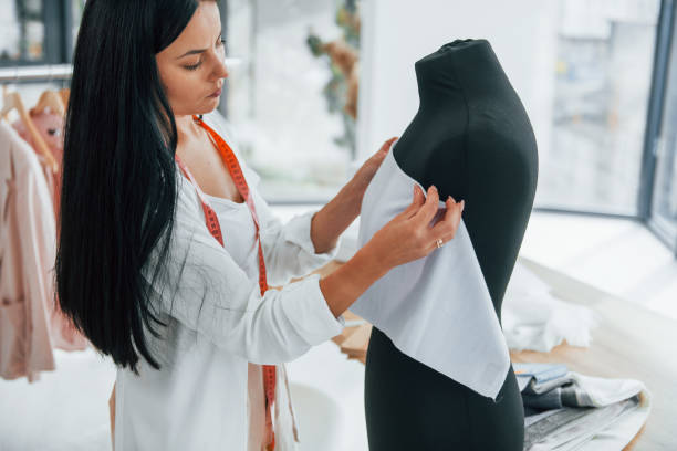 istock Using measuring tape. Seamstress is in her office that is with different clothes 1370118187