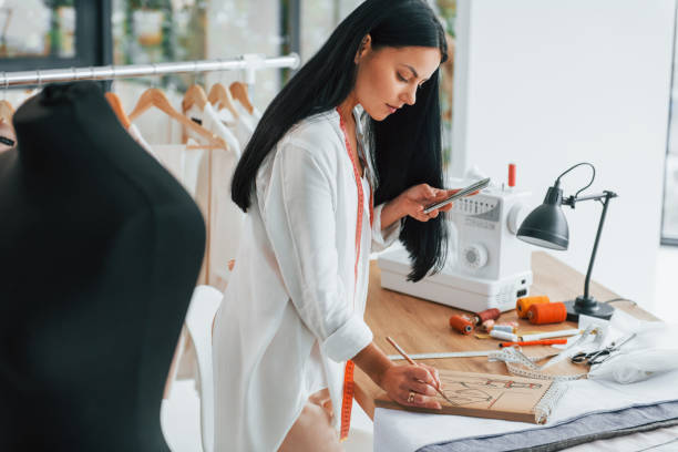 istock Notepad with picture. Seamstress is in her office that is with different clothes 1370118224