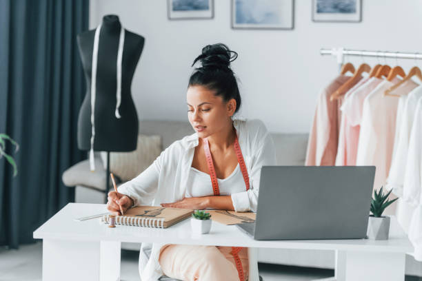 istock Busy day. Seamstress is in her office that is with different clothes 1370118337