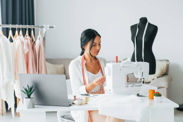 istock Professional sewing machine. Seamstress is in her office that is with different clothes 1370118566