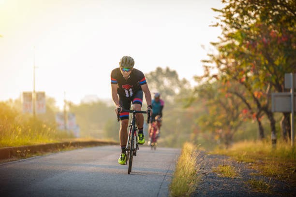 サイクリストは、アクションでリード,レース道路で自転車に乗ってフロントビューの男 - cycling shorts ストックフォトと画像