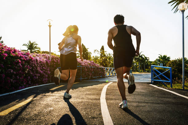 silhouette of couple running on the asphalt road in the morning silhouette of couple running on the asphalt road in the morning exercise stock pictures, royalty-free photos & images