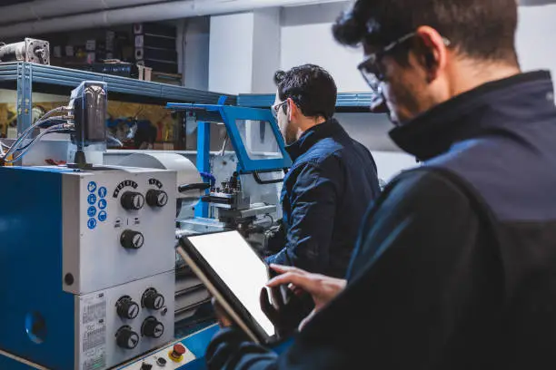 Photo of Mechanical technicians operative of cnc milling cutting machine center at tool workshop.