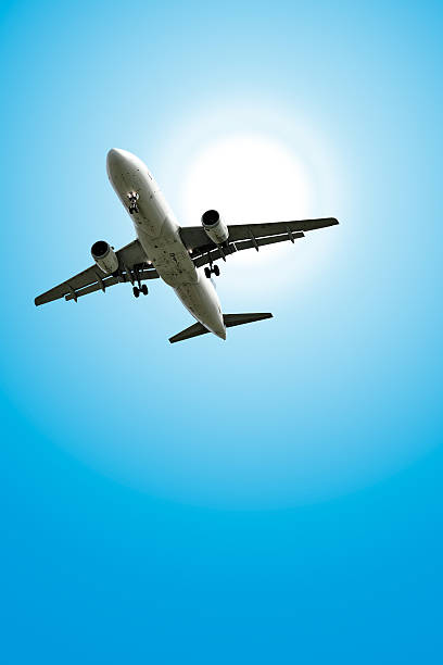 jet avion atterrissant dans le ciel ensoleillé - clear sky vacations vertical saturated color photos et images de collection