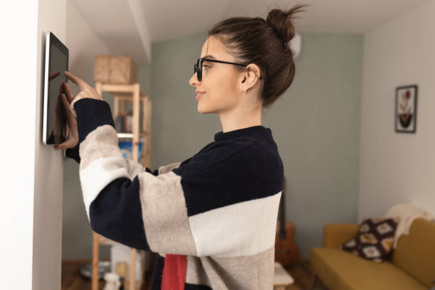 istock Young woman setting up the intelligent home system at her house 1370125501