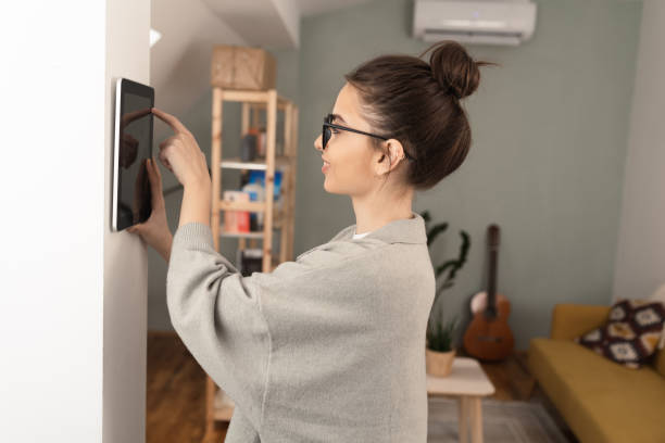istock Young woman setting up the intelligent home system at her house 1370125507