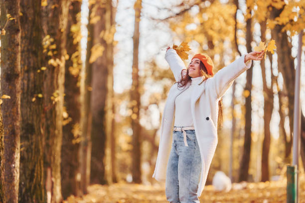 In red beret. Woman in white coat having fun in the autumn park stock photo