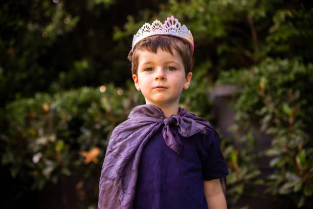 kleiner australischer junge, der verkleidungen in einem umhang und einer tiara oder krone spielt, verkleidet als könig, prinzessin oder prinz. kind, das seine vorstellungskraft nutzt - prances stock-fotos und bilder
