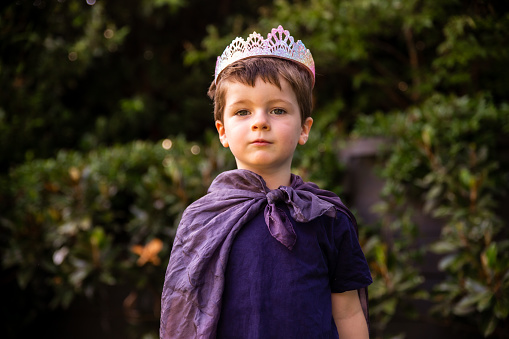 Niño australiano jugando a disfrazarse con una capa y una tiara o corona disfrazado de rey, princesa o príncipe. Niño usando su imaginación photo