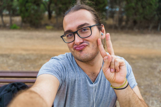 Man taking a selfie with his smartphone and pouting Man taking a selfie with his smartphone and pouting puckering stock pictures, royalty-free photos & images