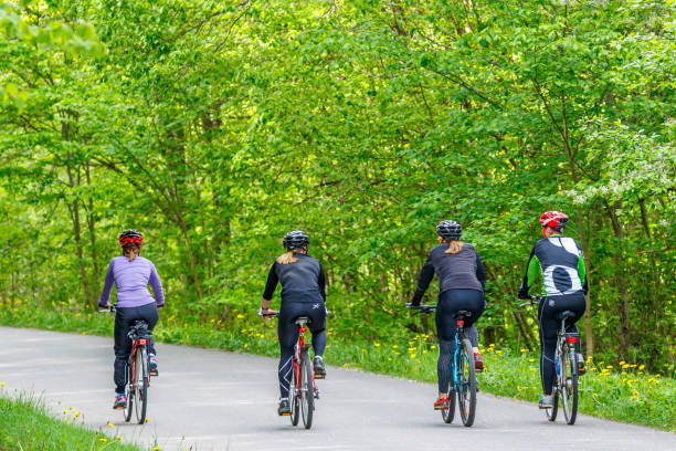 Falköping, Sweden - May 21, 2017: Women cycling on a road in a deciduous forest