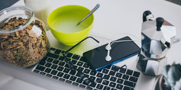 mesa para o café da manhã, cozinha ao fundo. dispositivos naturais de refeição e tecnologia. vista interior de uma casa aconchegante e moderna. millennial, juventude, trabalho em casa, educação domiciliar, conceito de trabalho remoto. - coffee pot audio - fotografias e filmes do acervo