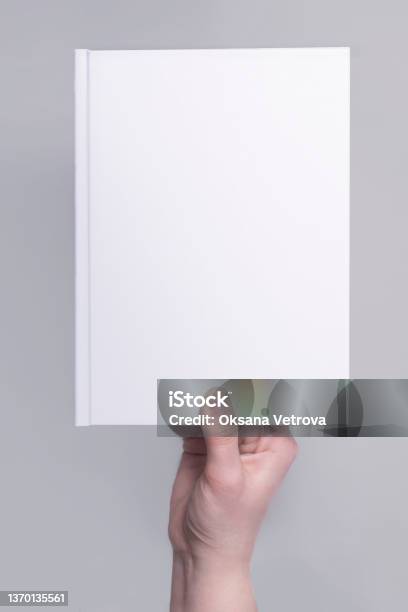 Mockup Of A White Hardcover Book Cover In Hand Applicable For Design Presentation Stock Photo - Download Image Now