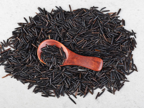 arroz preto em uma colher de pau em um fundo de arroz preto. close-up. vista superior - heart shape isolated isolated on white tea leaves - fotografias e filmes do acervo