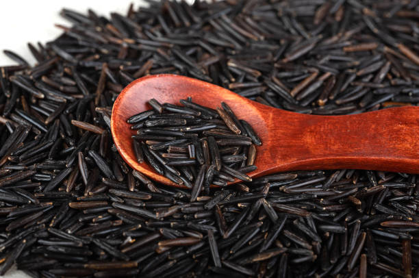 arroz preto em uma colher de pau em um fundo de arroz preto. close-up. vista superior - heart shape isolated isolated on white tea leaves - fotografias e filmes do acervo