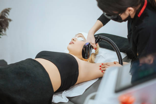 Young woman is having hair removal treatment with medical laser on woman arm stock photo
