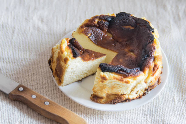 istock Basque Burnt San Sebastian Cheesecake with cutted piece on a white plate on light background, selective focus 1370146607