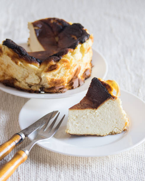 istock Basque Burnt San Sebastian Cheesecake with cutted piece on a white plate on light background, selective focus 1370146611