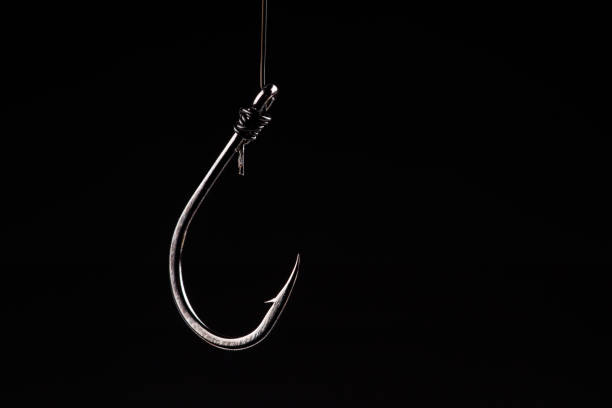 Fishing hook on a black background. trap, catch on, risk. Business concept idea Fishing hook on a black background. trap, catch on, risk. Business concept idea. fishing hook stock pictures, royalty-free photos & images