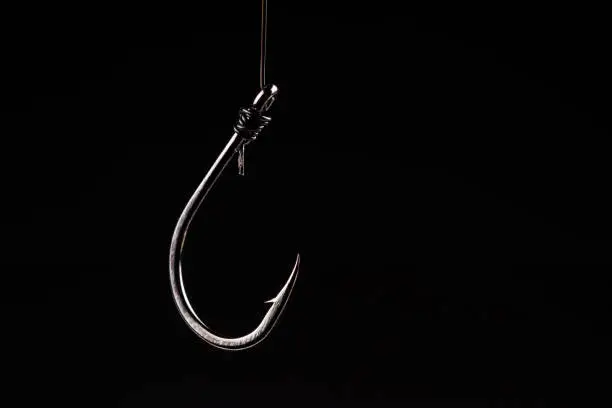Photo of Fishing hook on a black background. trap, catch on, risk. Business concept idea