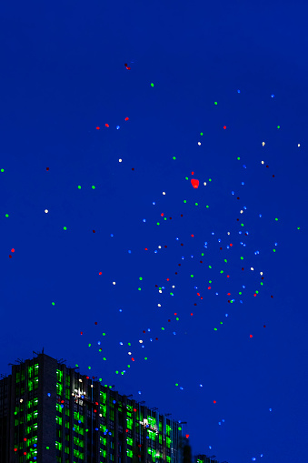 Colorful balloons fly in night sky above city in summer. Concept of holiday, happy birthday, wedding