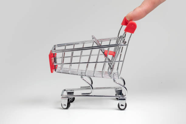 istock Human finger pushes empty grocery shopping cart. Isolated on white background. 1370157677