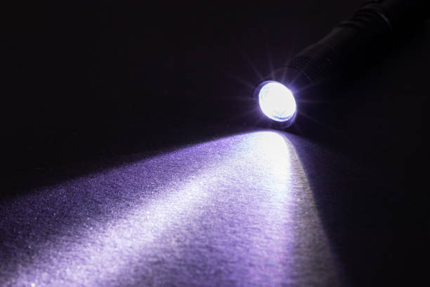 istock Flashlight and a beam of light in darkness. A modern led lamp with bright projection on dark table. Surface with copy space 1370157761