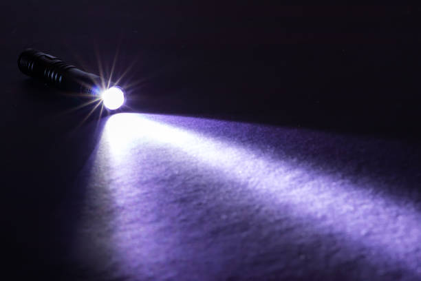 istock Flashlight and a beam of light in darkness. A modern led lamp with bright projection on dark table. Surface with copy space 1370157774
