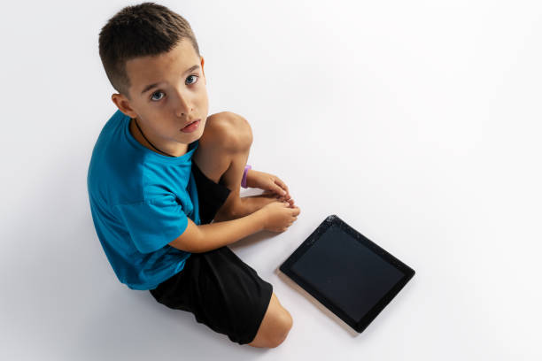 Adorable little girl of 4 years old is watching video on tablet with wireless children's headphones. Video communication. Listening to music.