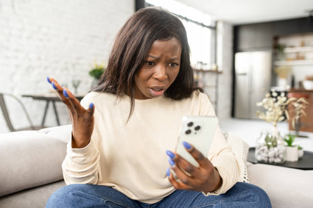 istock Angry stressed multiracial woman having unpleasant video call conversation, talks on the smartphone online and arguing, sits on the sofa and looks at the phone screen 1370162937