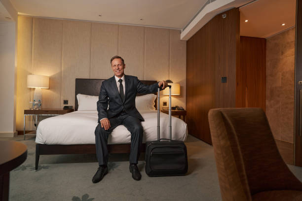 istock Friendly bussinesman smiling while sitting on hotel bed 1370165848