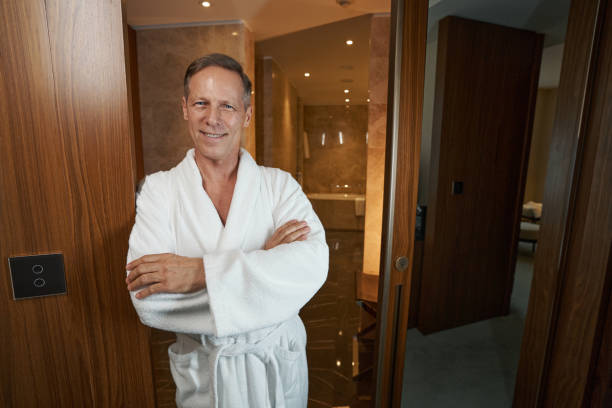 istock Pleasant man in cozy bathrobe posing for camera at hotel 1370165867