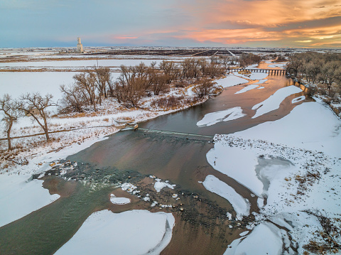 sunset over South Platte River with a diversion dam and farmland on Colorado plains near Milliken, aerial view with winter scenery