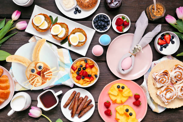 Fun Easter breakfast or brunch table scene. Top down view on a dark wood background. Fun Easter breakfast or brunch table scene. Top down view on a dark wood background. Bunny pancake, egg nests, chick fruit and assorted spring food items. bunny pancake stock pictures, royalty-free photos & images
